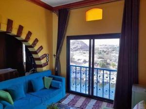 Resort Nubian Cataract في أسوان: غرفة معيشة مع أريكة زرقاء ونافذة كبيرة