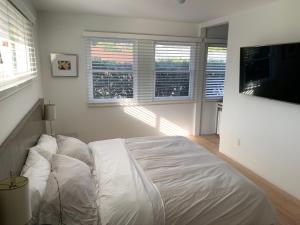 a white bedroom with a bed and a flat screen tv at Canyon View Cutie in San Diego