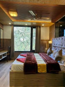 a bedroom with a large bed with a large window at HOTEL MA HEIGHTS in Dalhousie