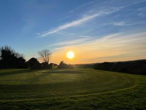 a sunset on a golf course with the sun setting at Wheal Amelia Lodge in Helston