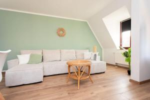 a living room with a white couch and a table at BOHO CHIC Markkleeberg, in Seenähe, Familien Apartment, 8 min ins Leipziger Zentrum mit S-Bahn, Großer TV mit X Box in Markkleeberg