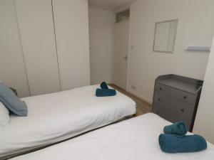 2 camas con toallas azules en un dormitorio en 19 Coedrath Park en Saundersfoot