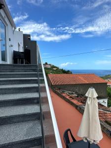 un balcón con una silla y algunas escaleras y el océano en Paradise Apartments III en Santa Cruz das Flores