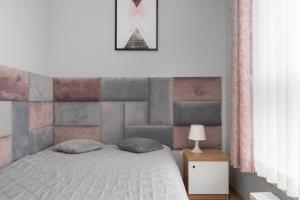 a bedroom with a bed with a pink and gray wall at Cosmo Apartments in Gdańsk