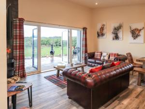 a living room with a leather couch and a fireplace at Pine Marten in Dornoch