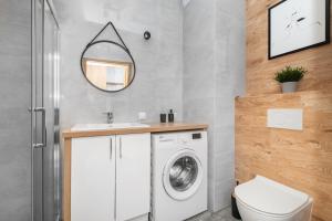 een badkamer met een wasmachine en een spiegel bij Cosmo Apartments in Gdańsk +73 foto's