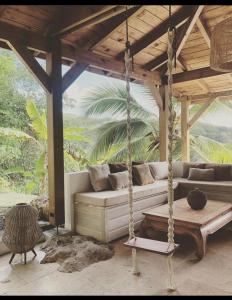 - une balançoire dans un pavillon avec un canapé dans l'établissement Le Loys Martinique, à Sainte-Anne