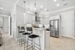 a kitchen with white cabinets and black bar stools at Do Grayt Things by 30A Escapes in Grayton Beach