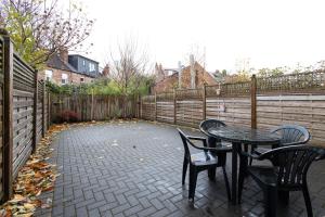 a patio with two tables and chairs and a fence at Modern 4 Bed Home with Free Parking & Garden in Manchester