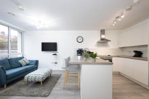 a kitchen and living room with a blue couch at Modern 4 Bed Home with Free Parking & Garden in Manchester