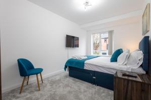 1 dormitorio con 1 cama y 1 silla azul en Modern 4 Bed Home with Free Parking & Garden, en Mánchester