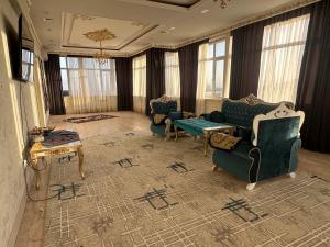 ein Wohnzimmer mit Sofas, einem Tisch und Fenstern in der Unterkunft The Rudaki Home stay in Duschanbe