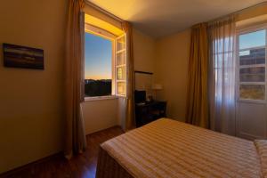 a bedroom with a bed and a large window at Hotel Due Colonne in Cagliari