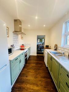 duża kuchnia z zielonymi szafkami i drewnianą podłogą w obiekcie NEW homely countryside escape w mieście Manningtree
