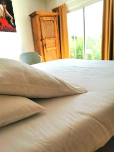 a close up of a white bed with a window at L'auberge Camarguaise in Saintes-Maries-de-la-Mer