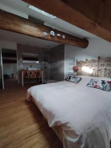 1 dormitorio con 1 cama blanca grande y suelo de madera en CHEZ COCO en Roquefort-de-Sault