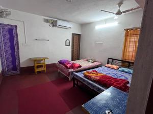 Cette chambre comprend 2 lits et une table. dans l'établissement SHANTINIR HOMESTAy, à Santiniketan