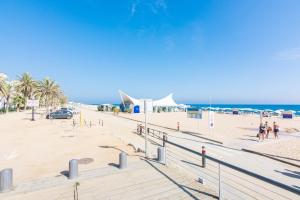a sandy beach with palm trees and the ocean at HomeHolidaysRentals Arlene in Calella