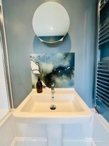 a bathroom with a sink with a painting on the wall at NEW homely countryside escape in Manningtree