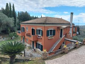 a large orange house with a palm tree in front of it at Nature retreat apartment in Kalafatiónes