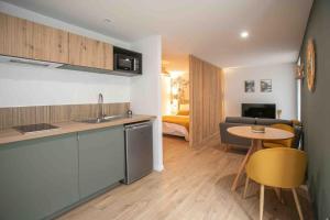 a kitchen and living room with a table and a couch at Studio cosy, neuf, hyper centre in Brantôme