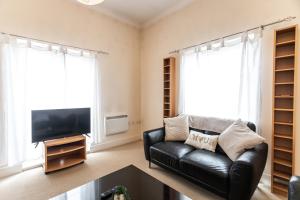 a living room with a black leather couch and a flat screen tv at April Disc - Long Stay - Contractors in Swindon