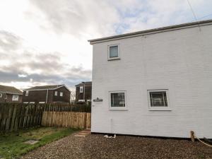a white building with two windows and a fence at 22 Longstone Park in Chathill