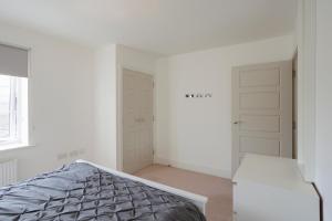 a white bedroom with a bed and two closets at Lovely Modern 1-Bed Flat in Kingston in Kingston upon Thames