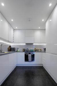 een witte keuken met witte kasten en een wastafel bij Lovely Modern 1-Bed Flat in Kingston in Kingston upon Thames