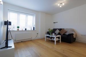 a living room with a black couch and a window at Lovely Modern 1-Bed Flat in Kingston in Kingston upon Thames