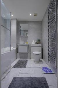 a bathroom with a tub and a toilet and a sink at Lovely Modern 1-Bed Flat in Kingston in Kingston upon Thames