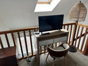 a living room with a television and a chair at 2 pièces duplex Issy Les Moulineaux Ascenseur internet in Issy-les-Moulineaux