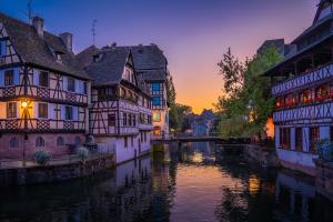 un grupo de edificios al lado de un río al atardecer en Au coeur du vignoble/centre ville, en Dorlisheim