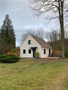 une maison blanche avec un arbre et une cour dans l'établissement A l’ombre des chênes, à Coye-la-Forêt
