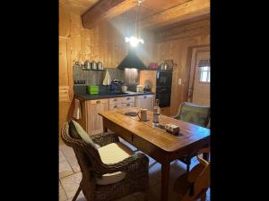 een keuken met een houten tafel en stoelen en een eetkamer bij La Chabraque in Le Barboux