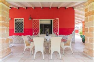 een patio met een tafel en stoelen voor een rode muur bij Villino Letizia in Nardò