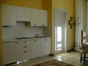 - une cuisine avec des placards blancs, un évier et une porte dans l'établissement Alpi Giulie, à Intra