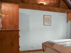 Un dormitorio con una pared blanca y una cama en The Old Dairy - Meadowbrook Farm, en Thame