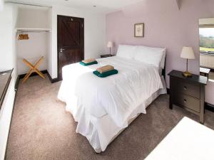 a bedroom with a large white bed and a night stand at Heather Cottage- Uk45889 in Farlam