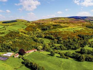 an aerial view of a hill with a house and a field at Heather Cottage- Uk45889 in Farlam