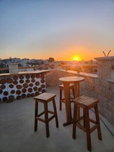 dos mesas y dos taburetes en una azotea con la puesta de sol en La Hacienda Cyprus, en Limassol