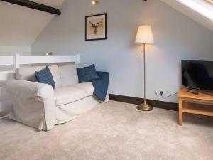 a living room with a white couch and a television at Bramble Cottage- Uk45891 in Farlam