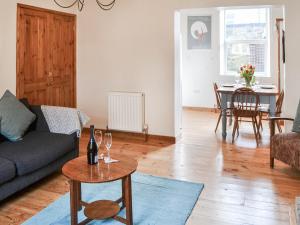 Pitmans Cottage في ريتون: غرفة معيشة مع أريكة وطاولة مع كؤوس للنبيذ
