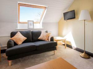a living room with a black couch and a window at Alder Cottage - Uk46154 in Farlam
