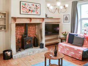 a living room with a fireplace and a tv at Pitmans Cottage in Ryton