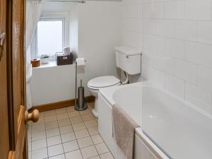 Pitmans Cottage في ريتون: حمام ابيض مع مرحاض وحوض استحمام