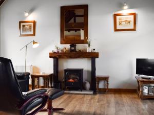 sala de estar con chimenea, silla y TV en Byre Cottage - Meadowbrook Farm, en Thame