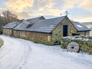 a stone barn in the snow on a dirt road at Bracken Cottage - Uk46155 in Farlam