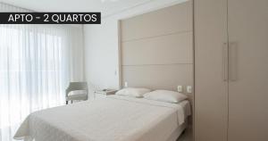 um quarto com uma cama branca e uma porta de vidro deslizante em Starlis Home - Versátil em Cuiabá