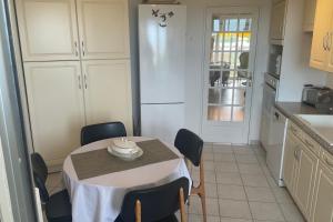 Il comprend une cuisine équipée d'une table avec des chaises et d'un réfrigérateur blanc. dans l'établissement top floor apartment with private park, à Montpellier